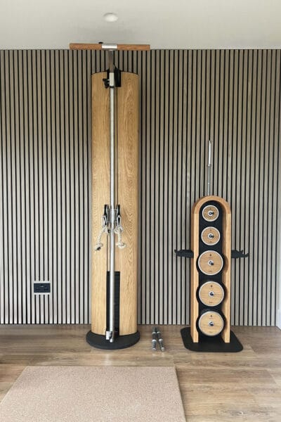 Modern home gym in Worcester with slatted wood wall and oak-framed fitness equipment designed by Megan Ace Interiors