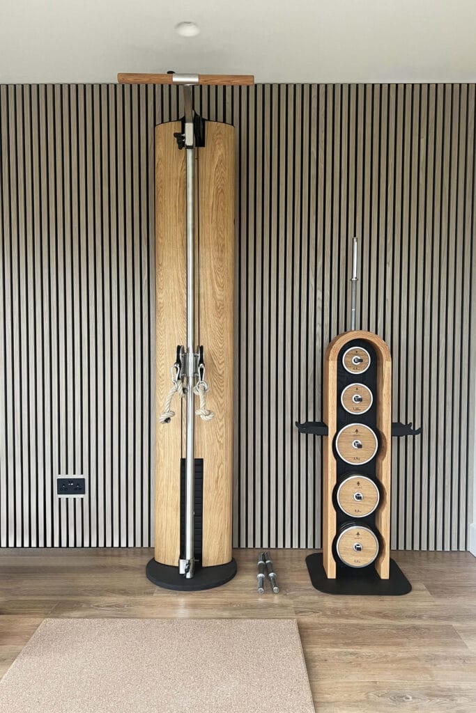 Modern home gym in Worcester with slatted wood wall and oak-framed fitness equipment designed by Megan Ace Interiors